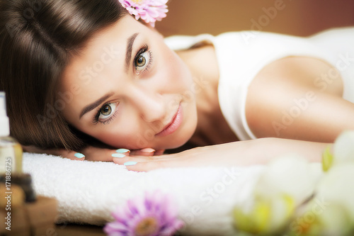 Massage. Beautiful woman at the spa. Gentle look. Flowers in hair. The concept of health and beauty. Dark background. Spa salon.