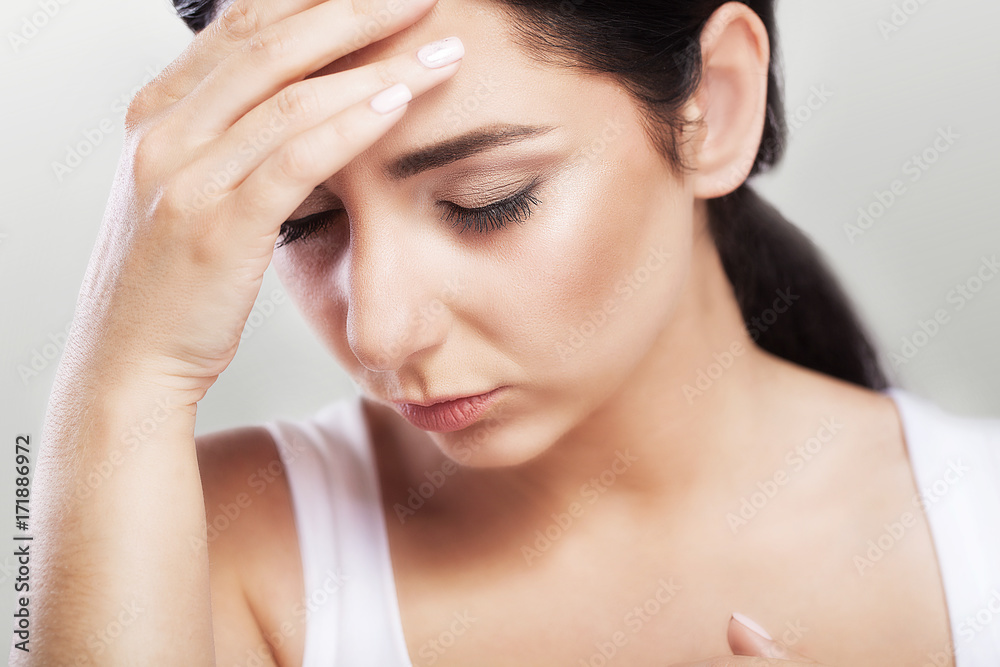 Portrait of a beautiful young brunette with bare shoulders, severe headaches, migraine, colds. The concept of treatment. Holds his hand to his forehead. Portrait of a beautiful young brunette with bare shoulders, severe headaches, migraine, colds. The concept of treatment. Holds his hand to his forehead.