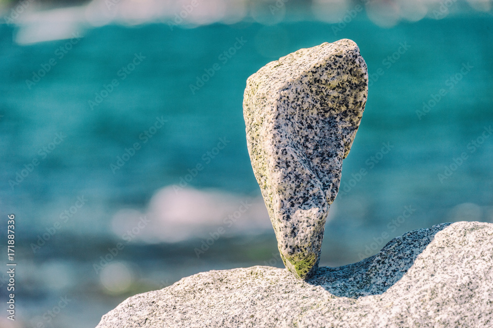 Triangular rock balanced on the tip in Vancouver rock stacking garden