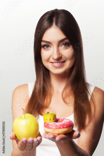 Diet. Emaciation. Girl smiles while holding an apple in her arms. Sports and fitness. The concept of health and beauty. On a gray background.