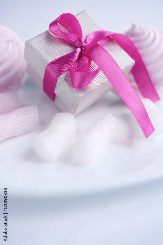 A box with a gift and decorative festive decorations on a light background A box with a gift and decorative festive decorations on a light background