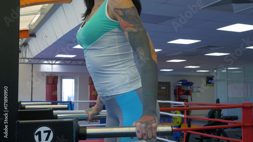Beautiful sexy female athlete doing push-ups on parallel bars in gym. Athlete woman workout out arms on dips horizontal parallel bars Exercise training triceps and biceps doing push ups. Athlete woman