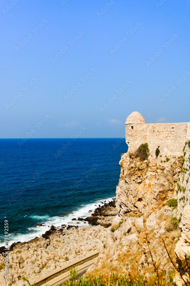 View of the walls of the Venetian Fortress (Fortezza) of Rethymno with a tower and the sea in the background against the blue sky. Rethymno, Crete, Greece