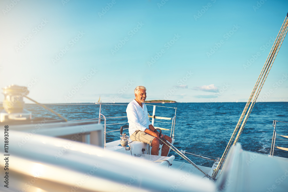 Smiling mature man sitting on the deck of his sailboat