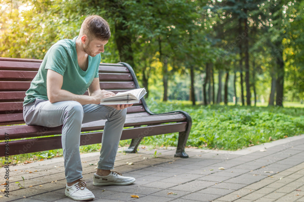 Obraz premium Young man reading book in the park
