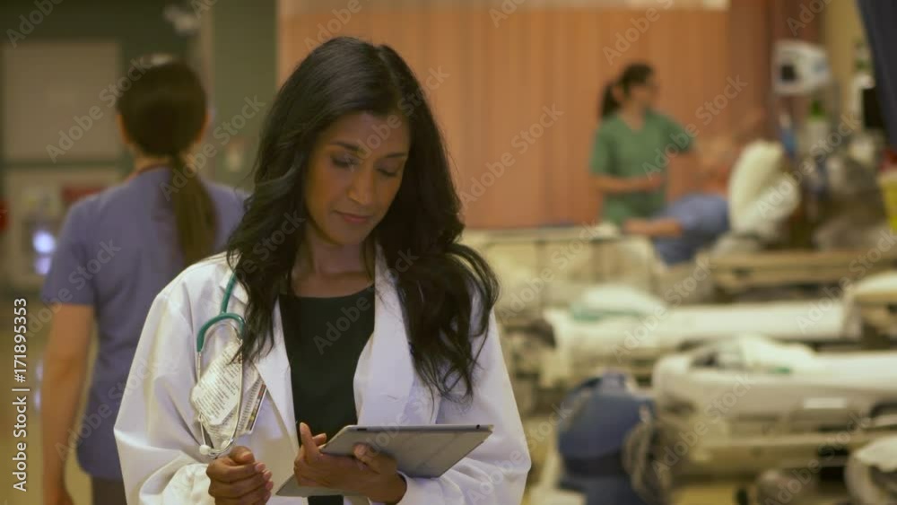 Modern female doctor uses a tablet computer in a busy hospital. Modern female doctor uses a tablet computer in a busy hospital.