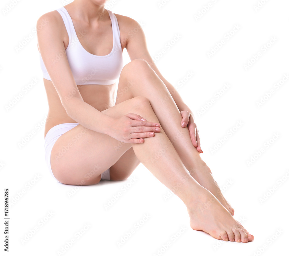 Young woman touching her legs on white background
