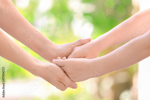 Mother and daughter holding hands together on blurred background, closeup © Africa Studio