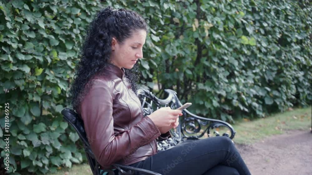 Brunette girl with curly hair with phone in hands Brunette girl with curly hair with phone in hands