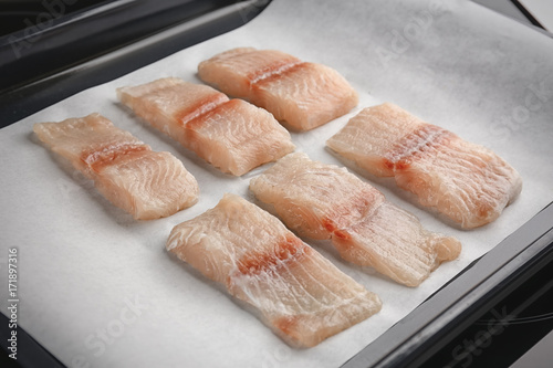 Many slices of raw fish fillet on baking paper