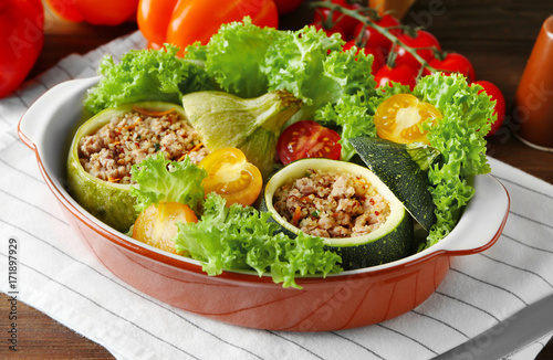 Quinoa stuffed zucchini served with salad and tomatoes on table