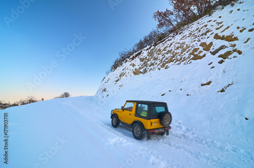 Mountain road covered with Snow and vehicle on it.