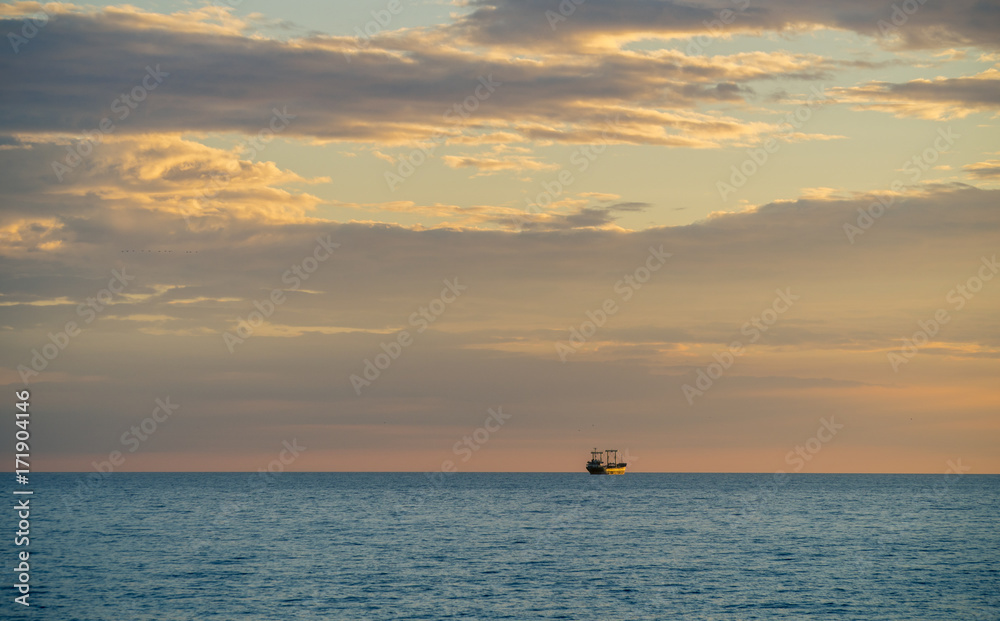 Ship and Cloudy Sky at Sunset Over The Sea