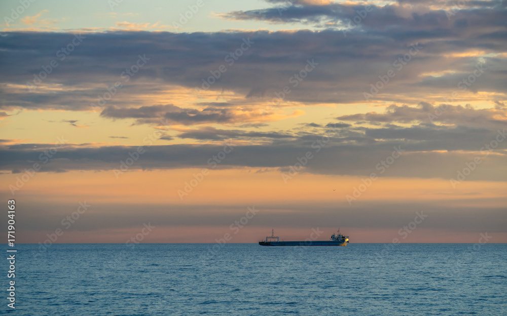 Ship and Cloudy Sky at Sunset Over The Sea