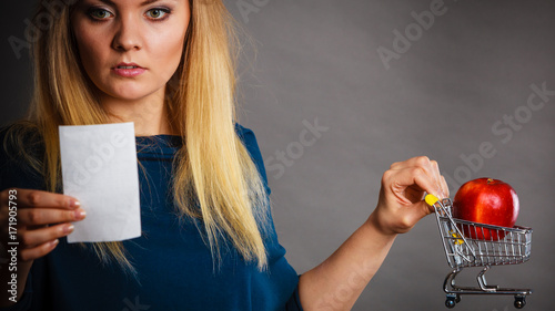 Worried woman holding shopping basket with fruits photo