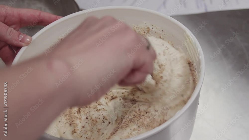 Hands of unrecognisable female confectioner mixing crumbs and whipped cream in mixing bowl using spatula, close up Hands of unrecognisable female confectioner mixing crumbs and whipped cream in mixing bowl using spatula, close up