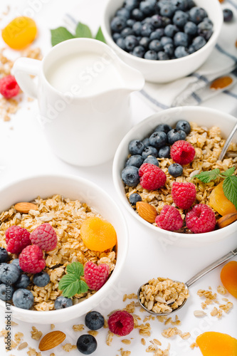 Homemade granola and healthy breakfast ingredients - milk, dried fruit and berries