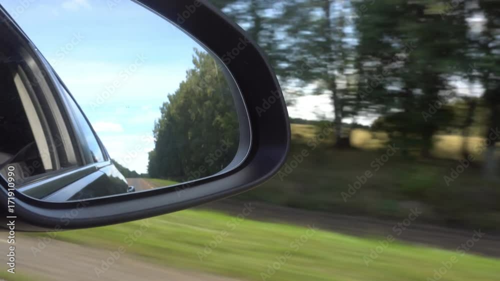 View of the road in the rearview mirror of a car. View of the road in the rearview mirror of a car.