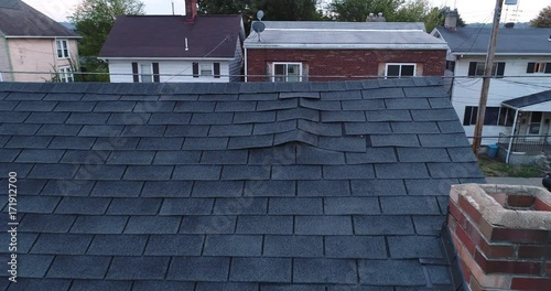 A simulated video feed of a roof inspector's unmanned drone examining a home's damaged shingled roof after a storm.  	