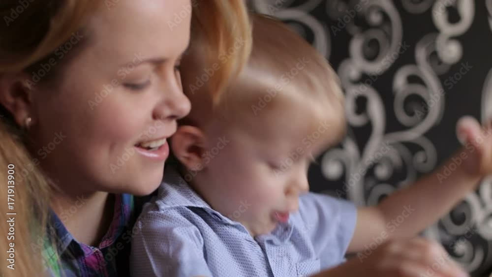 Young mother and her emotional son playing with plasticine while sitting at table. Young mother and her emotional son playing with plasticine while sitting at table.