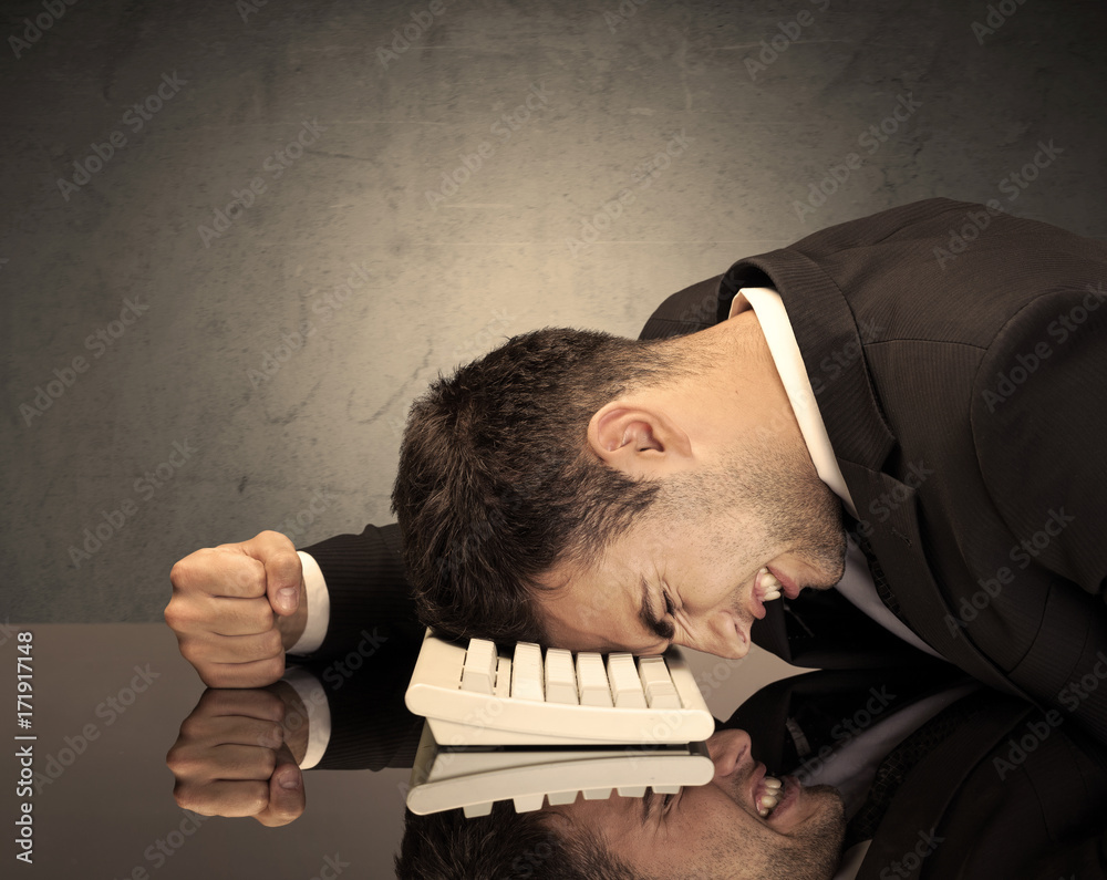 Obraz premium Frustrated businessman's head on keyboard
