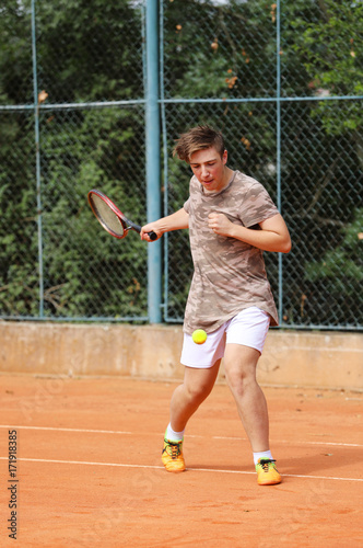 Teenage boy try to play forehand on the tennis court © sci