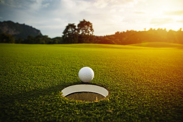 Acrylglasbilder Golf Golfball am Loch im Sonnenlicht  © kireewongfoto