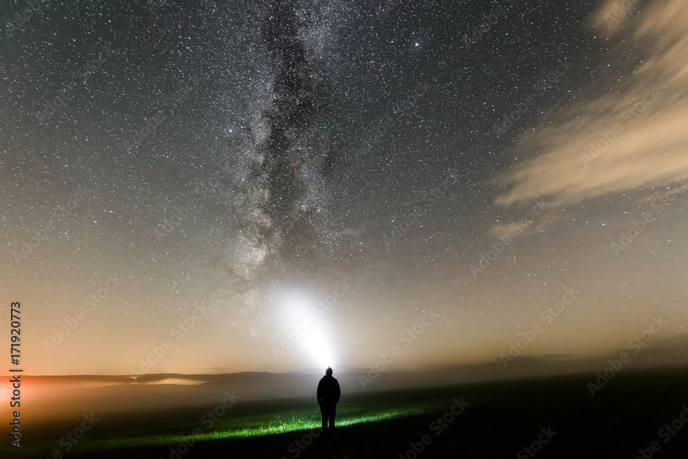 Mensch leuchtet mit Taschenlampe Nachts zur Milchstraße, Sternenhimmel mit Nebel