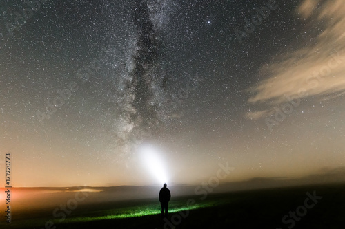 Fototapeta Naklejka Na Ścianę i Meble -  Mensch leuchtet mit Taschenlampe Nachts zur Milchstraße, Sternenhimmel mit Nebel