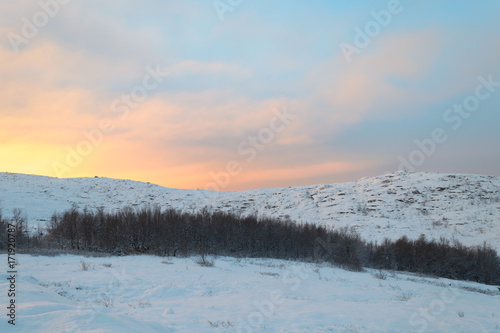 Sunset over hills covered with snow.