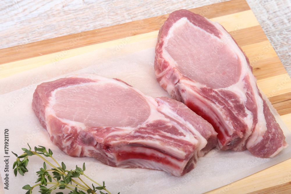 Raw pork chops, spices and rosemary on cutting board. Ready for cooking. Raw pork chops, spices and rosemary on cutting board. Ready for cooking.