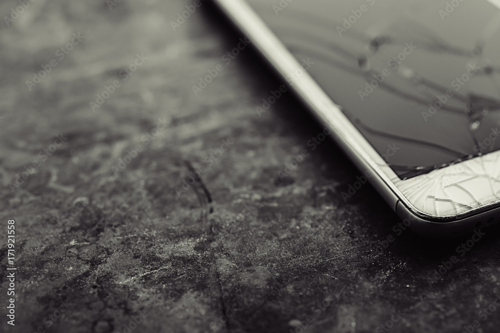 Smart phone with broken screen on dark background. Close-up. Smart phone with broken screen on dark background. Close-up.