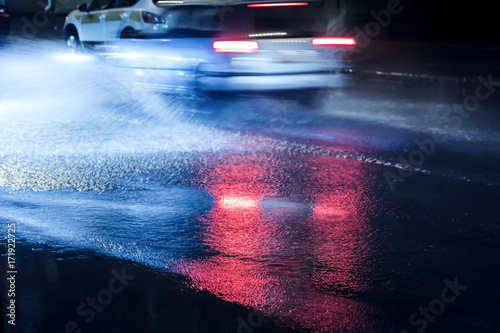 city traffic headlights reflecting in flooded road during rainy night. motion blur.