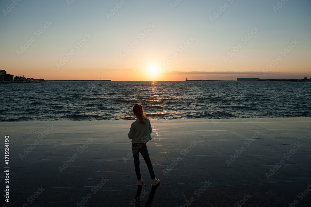 lonely little girl looking at the sea sunset