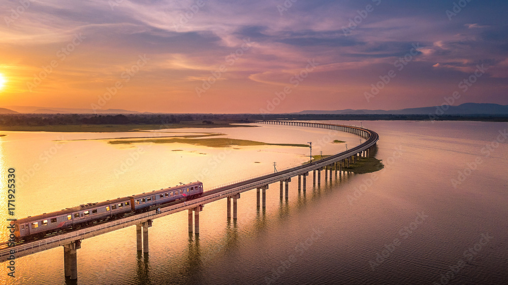 Aerial View The train is running on the bridge Over River Pa Sak Dam Lopburi Thailand and Beautiful sunset
