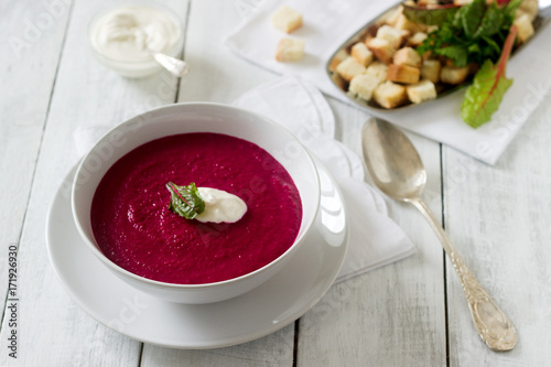 Obraz na płótnie Beet cream soup with sour cream and croutons and a white plate. Rustic style, selective focus. w salonie