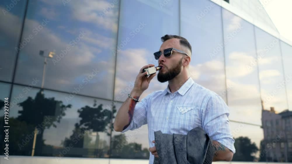 Confident well-dressed man with beard vaping an electronic cigarette Confident well-dressed man with beard vaping an electronic cigarette