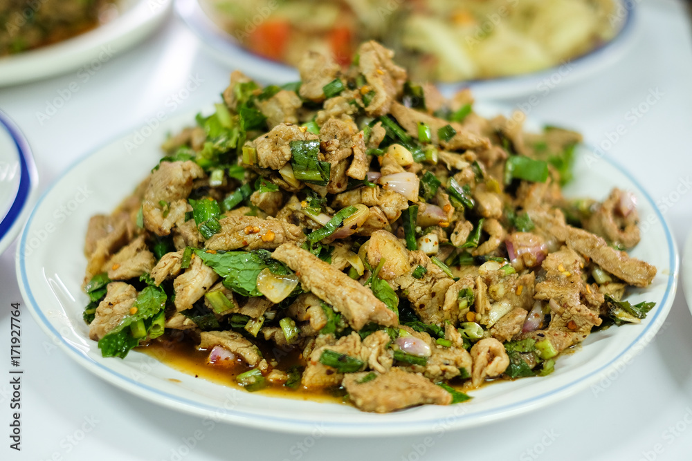 Homemade hot and spicy sliced grilled pork salad (Nam Tok Moo) serve on white plate for food background or texture - Thailand. Homemade hot and spicy sliced grilled pork salad (Nam Tok Moo) serve on white plate for food background or texture - Thailand.