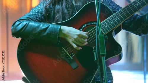 Woman's hands playing acoustic guitar on concert