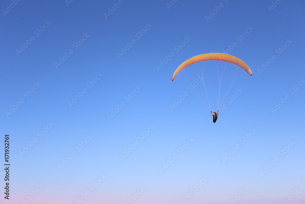A man is flying on a paraglider in the sky A man is flying on a paraglider in the sky