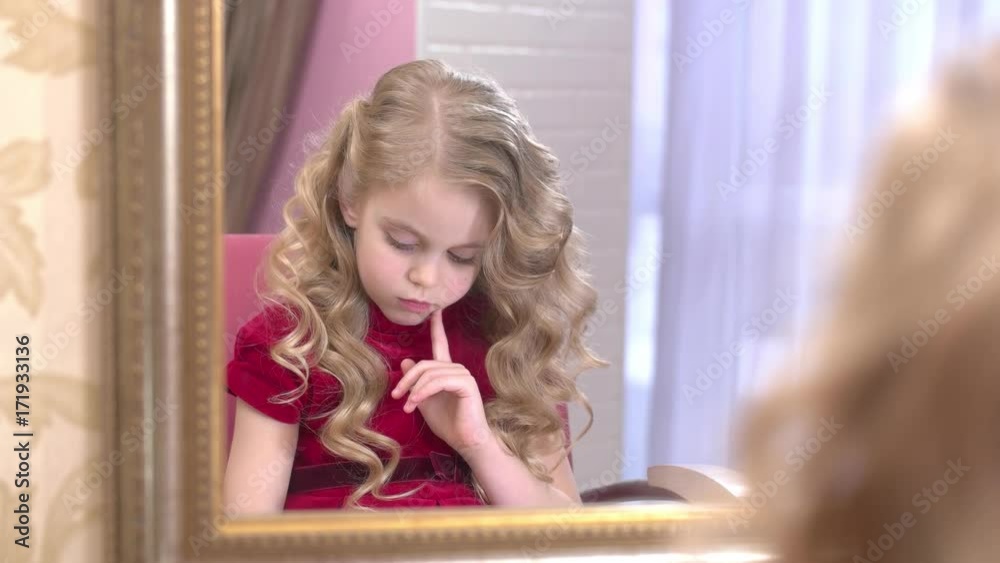 Thoughtful little girl reading magazine. Kid in a hairdressing salon. Thoughtful little girl reading magazine. Kid in a hairdressing salon.