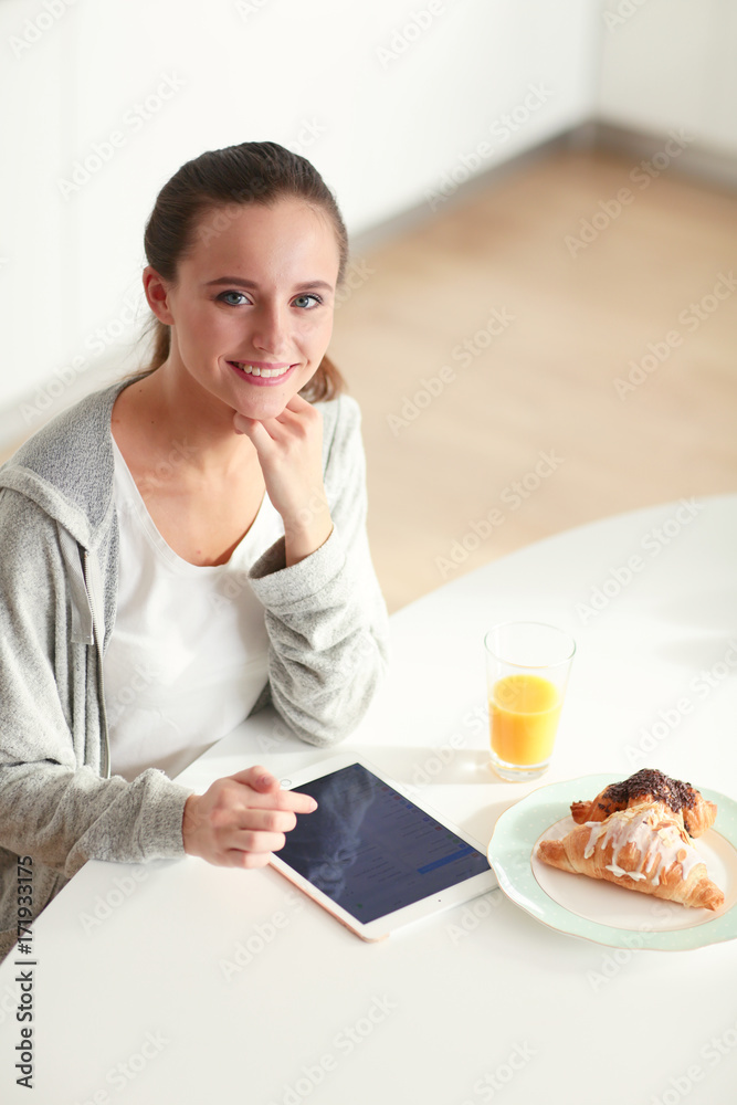 Young woman with orange juice and tablet in kitchen. Young woman with orange juice and tablet in kitchen.