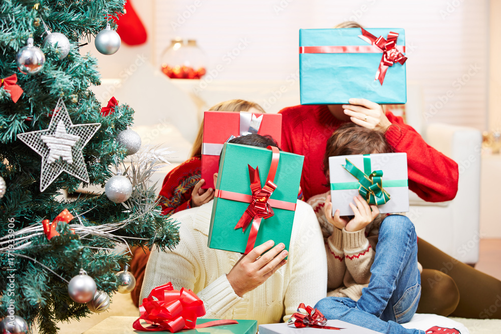 Familie hält Geschenke vor die Gesichter zu Weihnachten