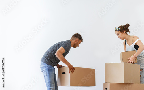 Moving out from apartment. Couple carrying cardboard boxes, working together as a team.