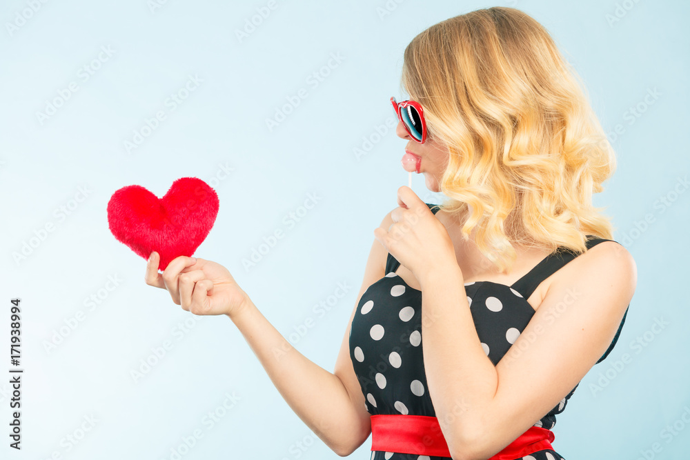 Woman holds red heart love symbol and lollipop candy Woman holds red heart love symbol and lollipop candy