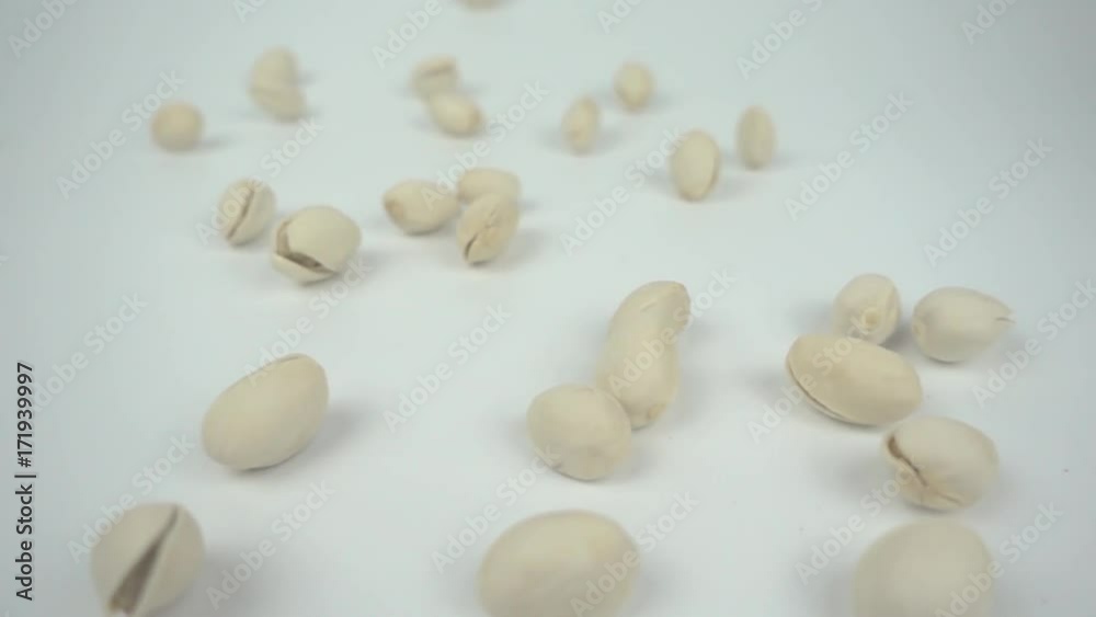 Pistachio nuts falling in slow motion from right on a white background Pistachio nuts falling in slow motion from right on a white background