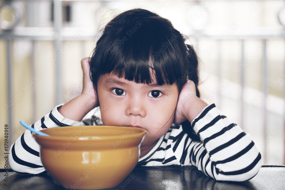 Asian children cute or kid girl student anorexia or sad with vacant and prop up or hand to cheek on food table for breakfast before going to school for study on vintage style Asian children cute or kid girl student anorexia or sad with vacant and prop up or hand to cheek on food table for breakfast before going to school for study on vintage style