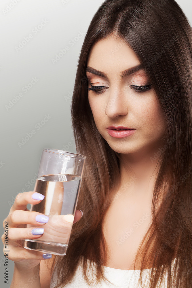 Young girl drinks water. Healthy look of the face. Portrait of a girl. The concept of beauty and health. On a gray background. Young girl drinks water. Healthy look of the face. Portrait of a girl. The concept of beauty and health. On a gray background.