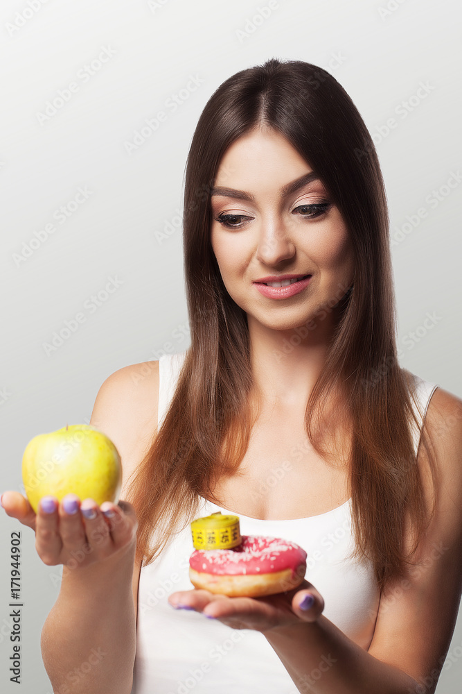 Harmful and healthy eating Young girl chooses between harmful and healthy food Diet Concept of health and beauty On a gray background. Harmful and healthy eating Young girl chooses between harmful and healthy food Diet Concept of health and beauty On a gray background.