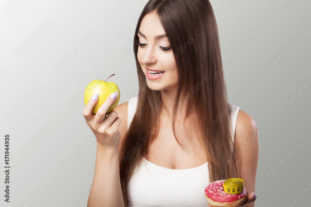 Harmful and healthy eating Young girl chooses between harmful and healthy food Diet Concept of health and beauty On a gray background. Harmful and healthy eating Young girl chooses between harmful and healthy food Diet Concept of health and beauty On a gray background.